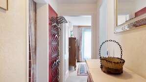 Un pasillo con una puerta roja, una cesta tejida y un espejo en la pared.
