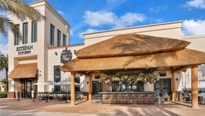 A restaurant with an outdoor seating area, a thatched roof, and a sign reading "ESTEFAN KITCHEN". - The Flamingo Nest - Kid Friendly (Kissimmee)