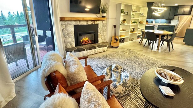 Una sala de estar moderna con chimenea, un comedor y una cocina.