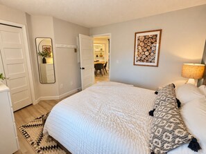 Une chambre à coucher avec un grand lit, une lampe de chevet, un miroir et une porte donnant sur un coin repas.