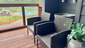 Un balcón con sillas de mimbre y plantas en macetas.