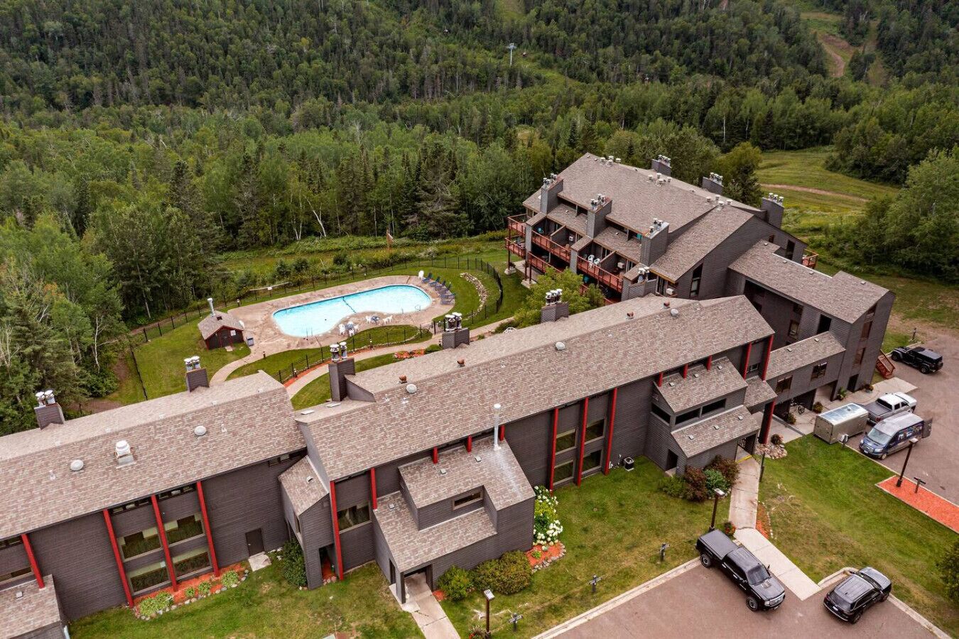 Un bâtiment moderne doté d’une piscine, entouré de verdure et situé dans un paysage vallonné.