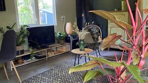 Un salon avec un téléviseur, un canapé, un fauteuil et diverses plantes.