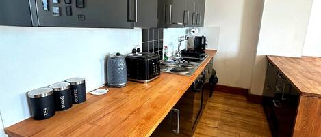 Una cucina moderna con piano in legno, elettrodomestici in acciaio inossidabile e una grande finestra.