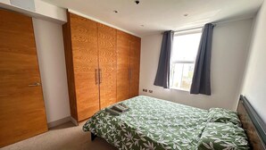 Une chambre à coucher avec un lit, une armoire et une fenêtre avec des rideaux.