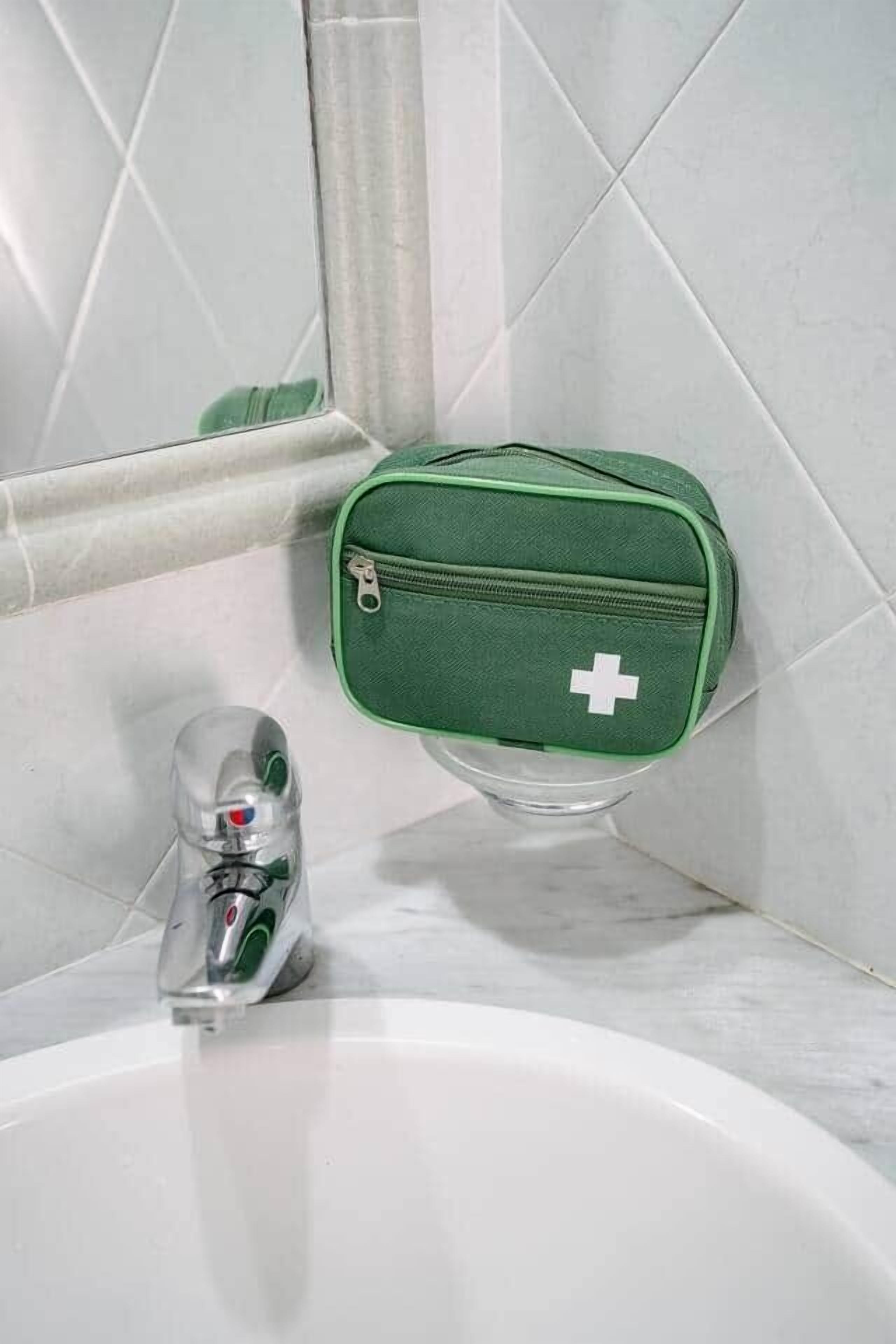A bathroom with a green first aid kit, a clear glass bottle, and a white sink.