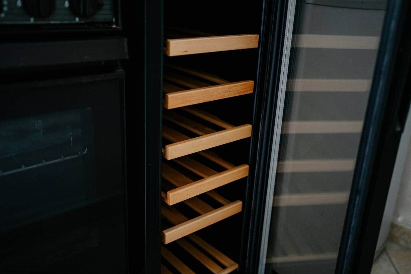 A wine rack with multiple slots, a black cabinet, and a glass door.