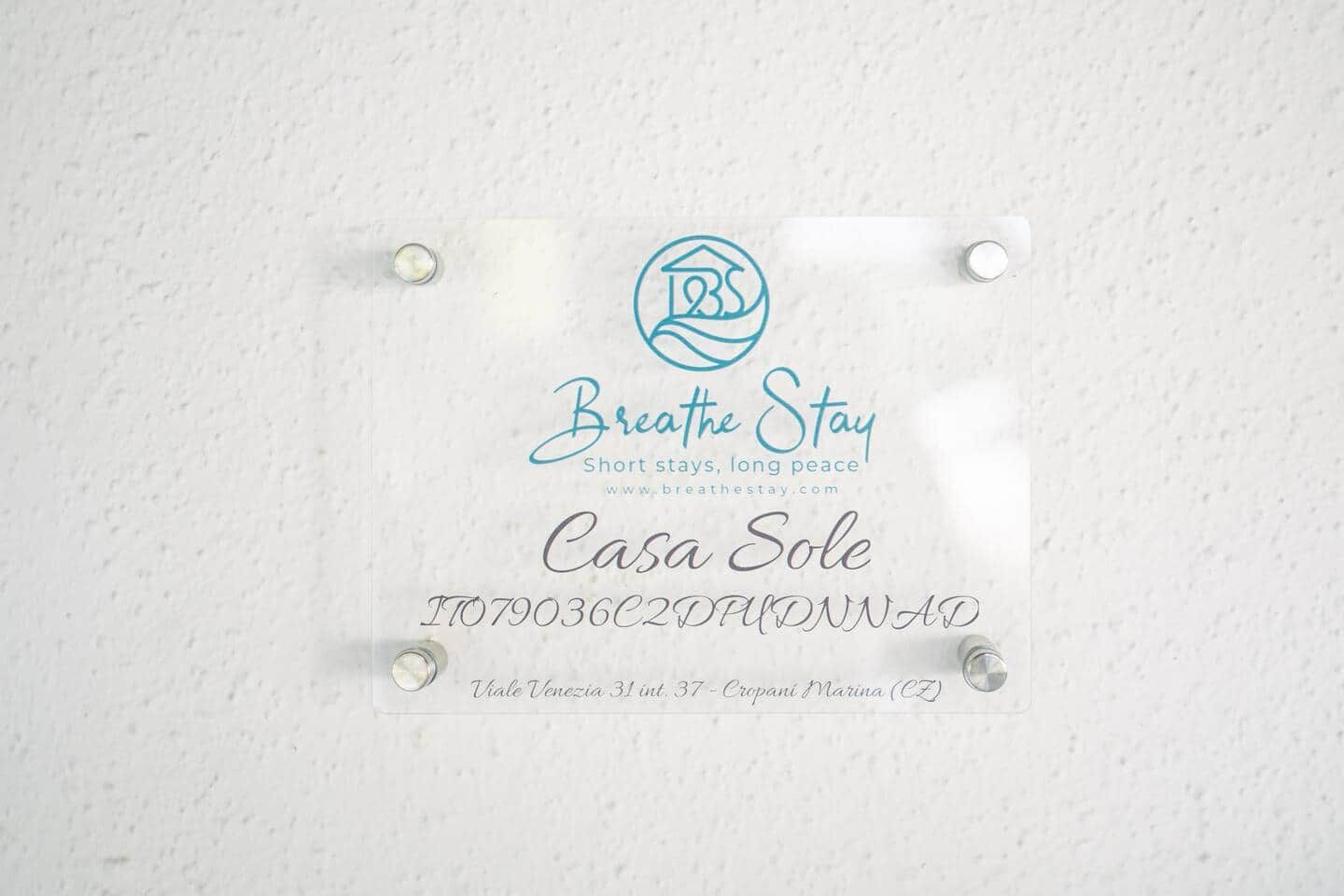 Een bord met de tekst 'Breathe Stay', een logo, de naam 'Casa Sole' en een telefoonnummer.