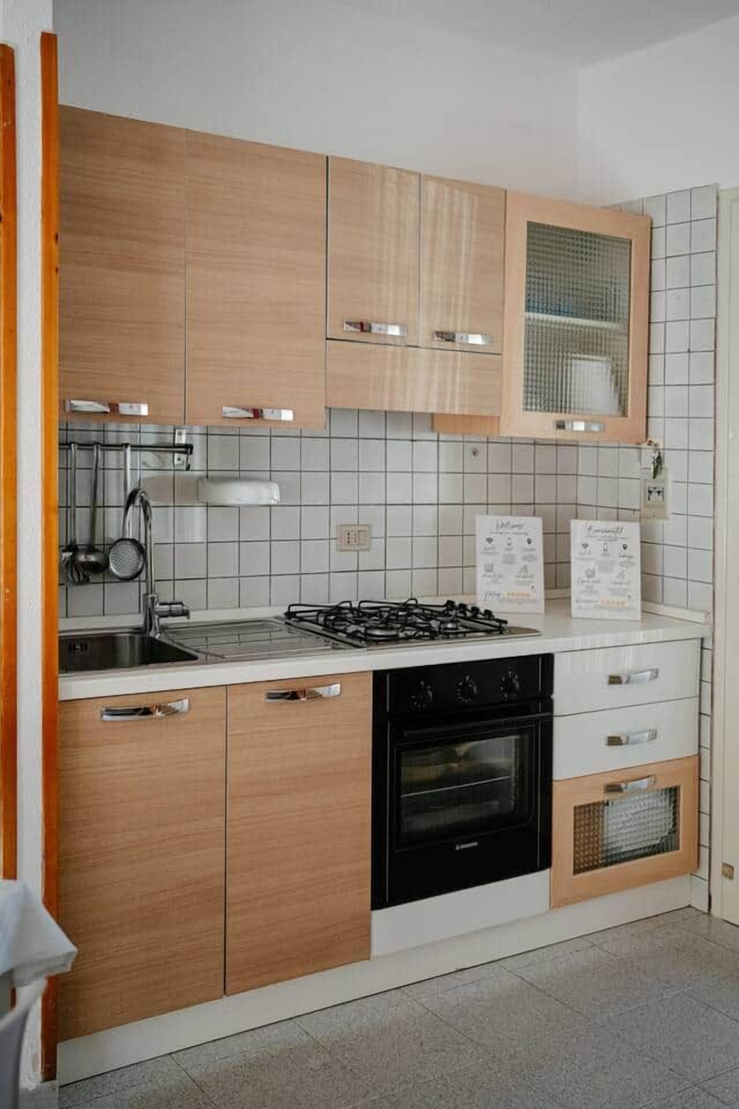 A kitchen with wooden cabinets, a gas stove, a sink, and a built-in oven.