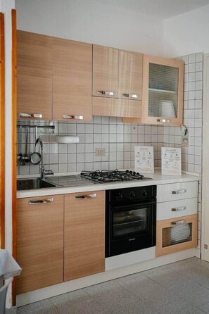 Une cuisine avec des meubles de rangement en bois, une cuisinière à gaz, un évier et un four encastré.