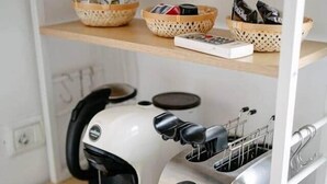 Cuina amb torradora i cafetera sobre una estant de fusta.