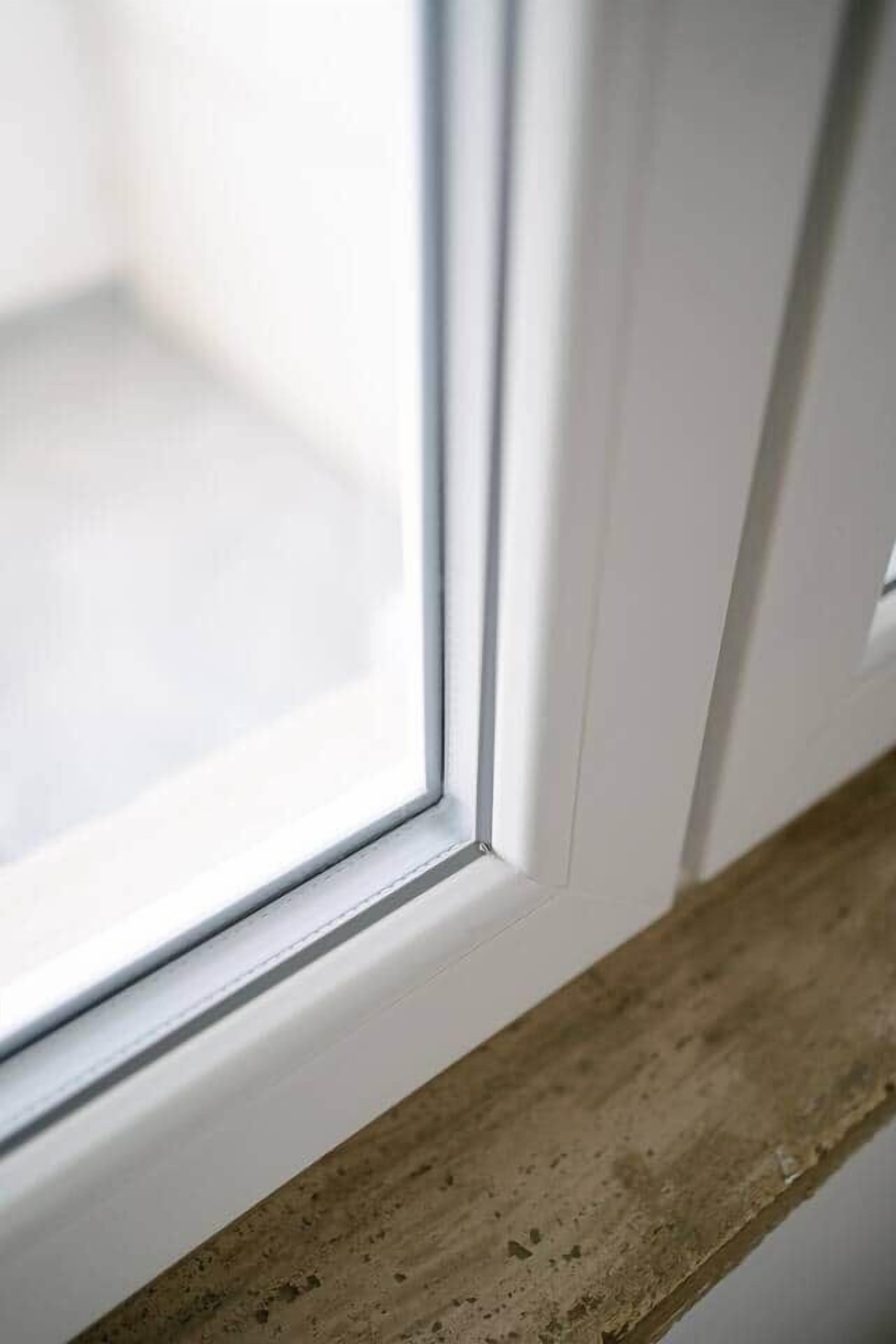 Ein Detailaufnahme eines Fensterrahmens mit einem Holzbrettchen.