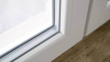 Ein Detailaufnahme eines Fensterrahmens mit einem Holzbrettchen.