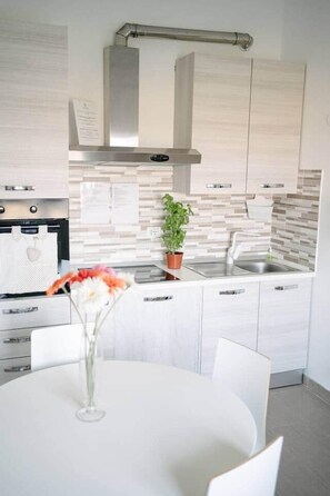A modern kitchen with white cabinets, a stainless steel range hood, and a tiled backsplash. - Casa Cleo - Ocean & Pine Forest (Villaggio Carrao)