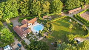 An aerial view of a residential property with a swimming pool, a detached garage, and a well-maintained lawn.