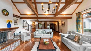 A spacious living room with a fireplace, a sofa set, a coffee table, and a chandelier.