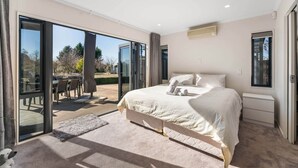 Ein Schlafzimmer mit einem großen Bett, einer Schiebetür zu einer Terrasse und einem Deckenventilator.