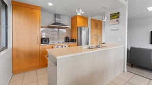 Eine moderne Küche mit Holzausbau, Edelstahlgeräten und einer zentralen Kochinsel mit Spüle.