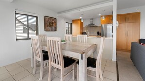 Eine moderne Küche mit Holzschränken, einem Edelstahlkühlschrank und einem Essbereich mit Holztisch und -stühlen.