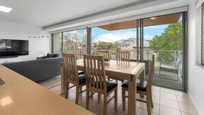 Eine moderne Wohnung mit Essbereich, einer Couch und einem Fernseher.
