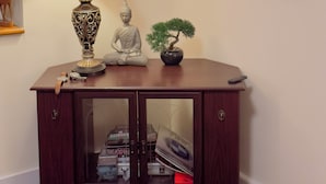 Ett mörkt träkonsolbord med en lampa, en Buddha-staty och ett bonsaiträd.