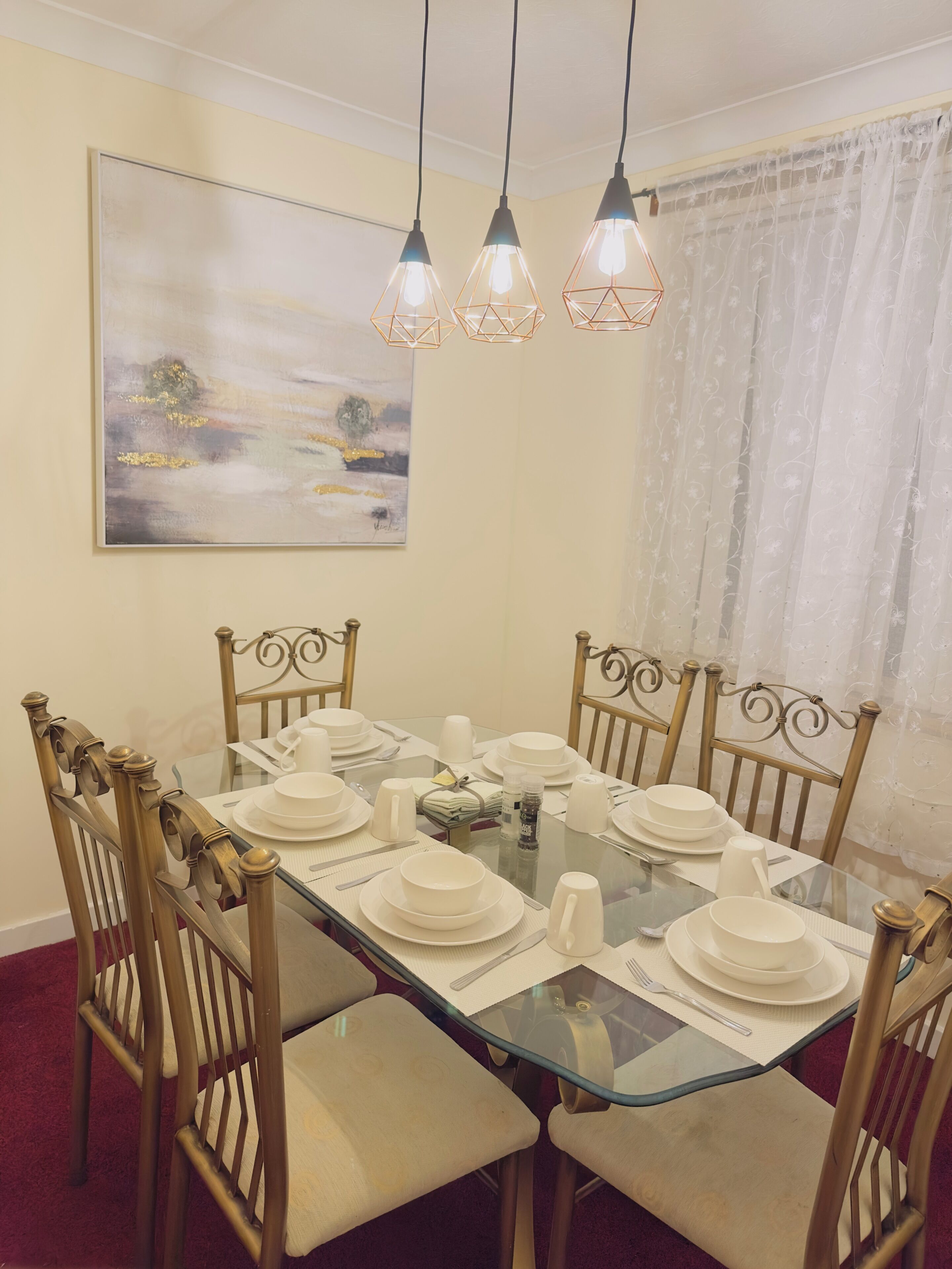 A dining area with a glass table set for six, surrounded by wooden chairs with cushioned seats.
