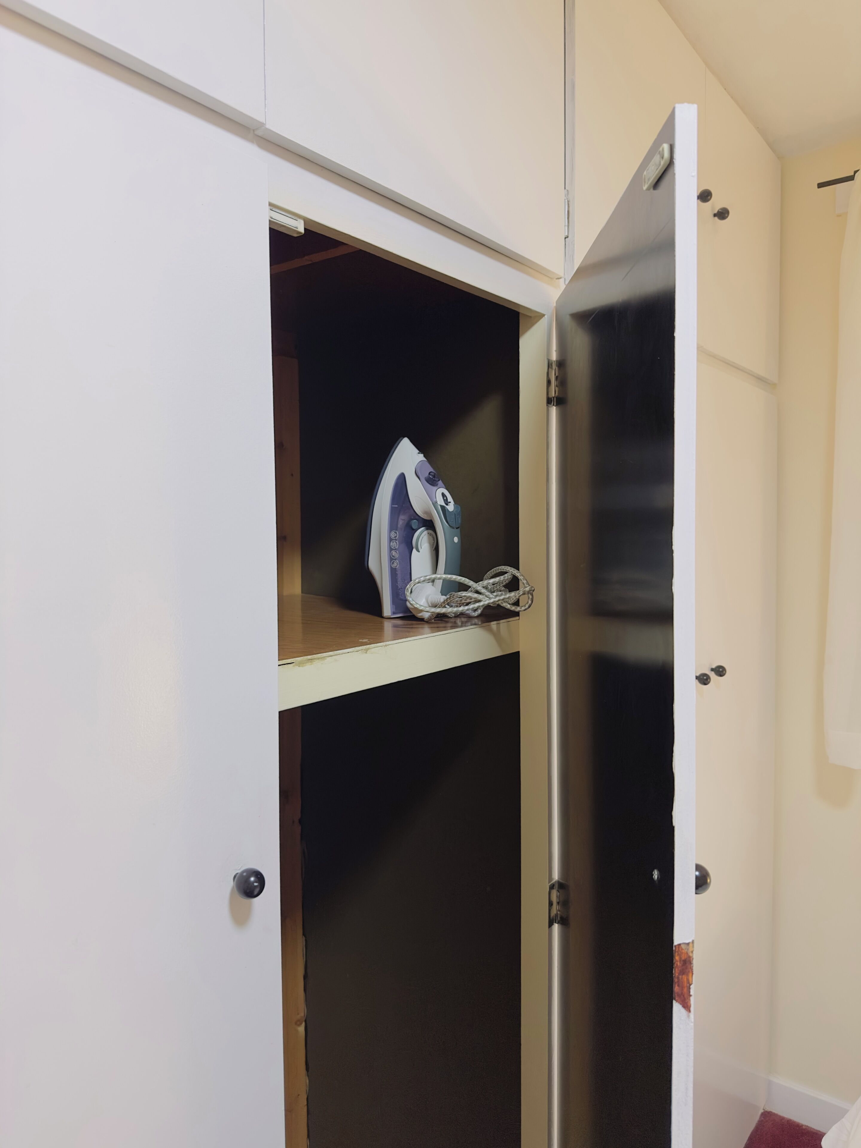 A wardrobe with a hanging rack and a door partially open.