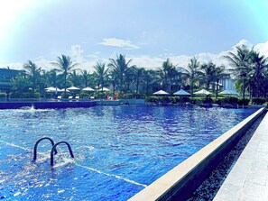 Una piscina al aire libre, sombrillas, sillones reclinables de piscina