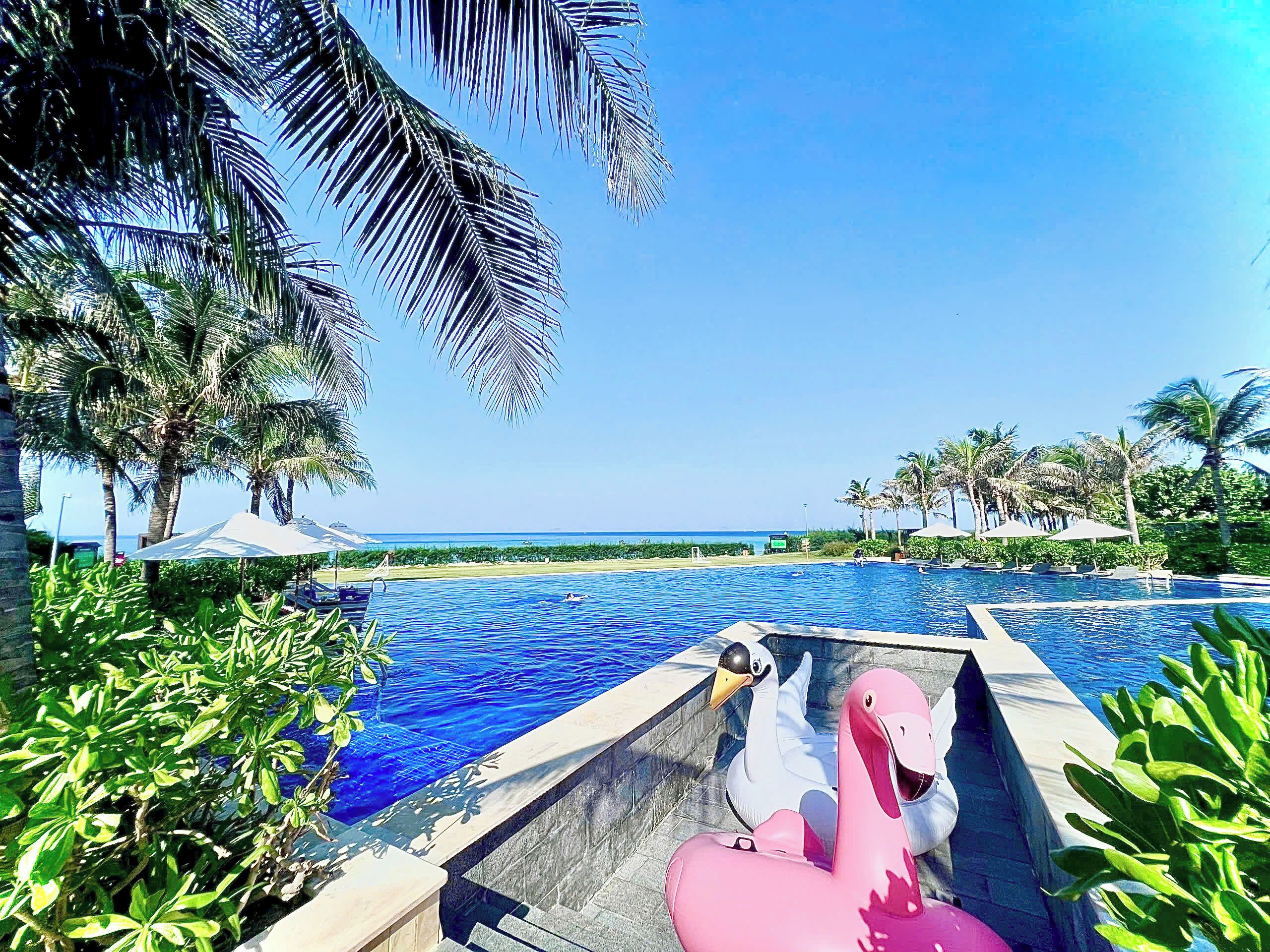Una piscina al aire libre, sombrillas, sillones reclinables de piscina