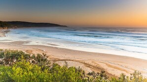 A beach with waves, greenery, and a clear sky. - Elysian Escape  - 4 Pools, Lakeside, Raffertys Res (Cams Wharf)