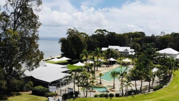 A resort with a pool, palm trees, and a view of the sea. - Elysian Escape  - 4 Pools, Lakeside, Raffertys Res (Cams Wharf)