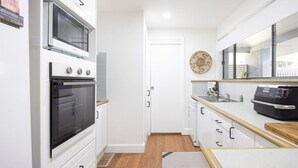 A modern kitchen with white cabinetry, a built-in oven, a microwave, and a black range hood. - Elysian Escape  - 4 Pools, Lakeside, Raffertys Res (Cams Wharf)