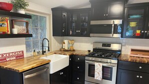 Une cuisine moderne avec des meubles de couleur sombre, des appareils électroménagers en acier inoxydable et un plan de travail en bois.