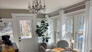 Un coin repas avec une table ronde, des chaises, un lustre et une plante en pot.