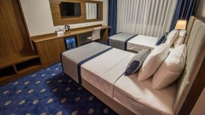 Une chambre d’hôtel avec deux lits, un bureau, une télévision et une fenêtre avec des rideaux.