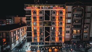 Un hôtel à plusieurs étages, doté d’une enseigne lumineuse indiquant « Looks Hotel & Nanaz Restaurant ».