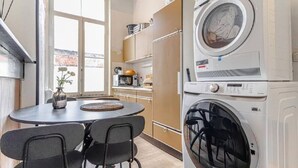 A compact kitchen with a dining area, a washing machine, and a large window.