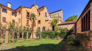 Un patio con muro de ladrillo, una palmera y un edificio con múltiples ventanas y balcones.