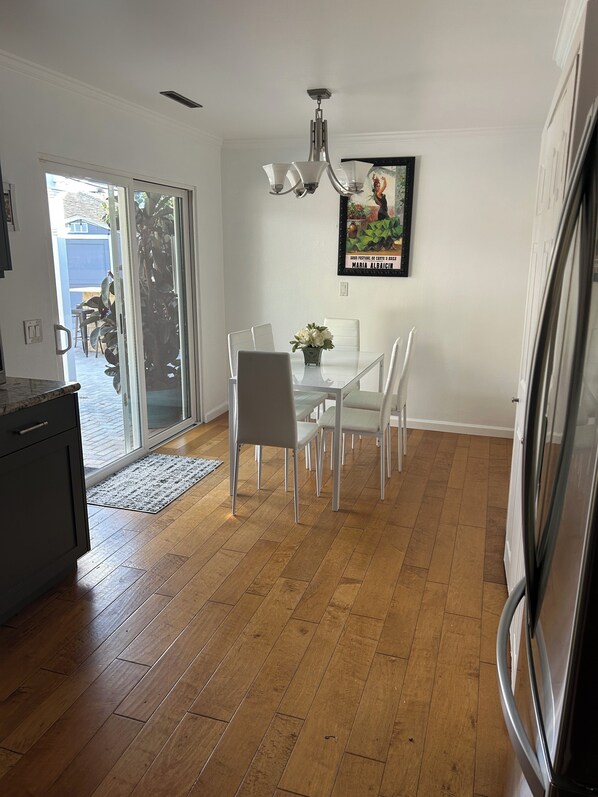 Een moderne keuken met een eethoek, met een glazen deur naar een terras, een kroonluchter en een lijstwerk aan de muur.