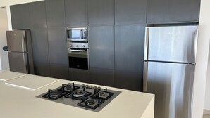 A modern kitchen with a built-in oven, a microwave, a gas stove, and a stainless steel refrigerator.