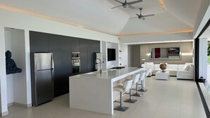 A modern kitchen with a central island, built-in appliances, and a seating area with a white sofa and bar stools.
