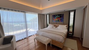 A bedroom with a large bed, a chair, a bench, and a painting on the wall.