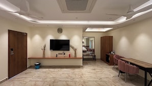 Una habitación de hotel moderna con piso de mármol, mobiliario de madera, televisor de pantalla plana y ventilador de techo.