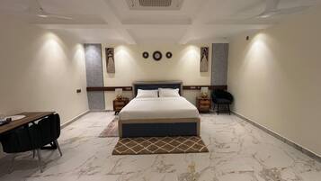 A modern bedroom with a large bed, a desk, and a chair.