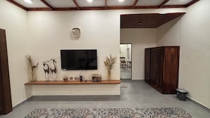 Una sala de estar moderna con un televisor de pantalla plana, objetos decorativos, un mueble de madera y una alfombra estampada.