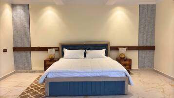 A neatly arranged bedroom with a large bed, two bedside tables with lamps, and a marble-patterned floor.