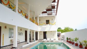 Un edificio moderno con piscina central, varios balcones y plantas en macetas.
