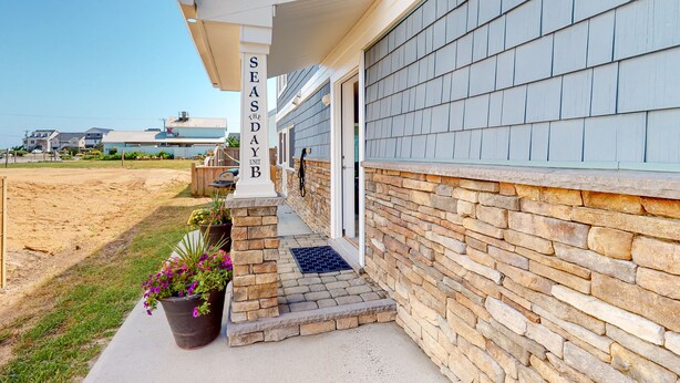 A building with a stone exterior and a covered porch. - KH3111B: Seas the Day | Walk to Beach | Patio | Kitchenette (Kitty Hawk)
