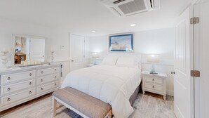 A bedroom with a bed, bedside tables, a dresser, a bench, a mirror, and a framed picture on the wall. - KH3111B: Seas the Day | Walk to Beach | Patio | Kitchenette (Kitty Hawk)