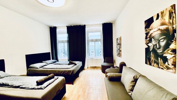 Un dormitorio moderno con sofá, dos camas, un ventanal grande y un cuadro en la pared.